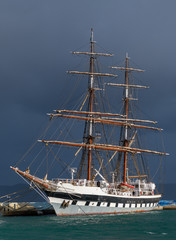 White two-masts sailing ship moored in port.