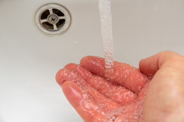 Fototapeta premium Mann hält seine Hand unter laufenden Wasserhahn