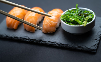 Top view of sushi rolls and sashimi set served on stone slate.