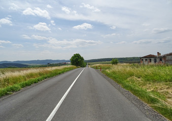Asphalt road. The green field. Blue sky