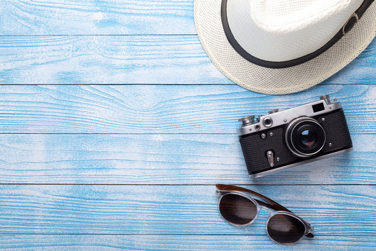 Summer flat lay. Straw hat, retro camera and sunglasses, coconut on blue background, top view. Holiday concept.