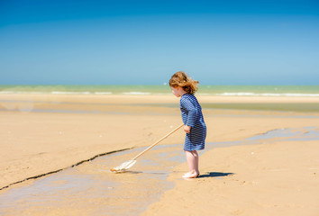 cute little girl and her net for shrimp fishing on the beach