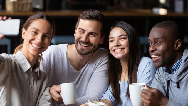 Happy diverse friends make selfie in cafe together