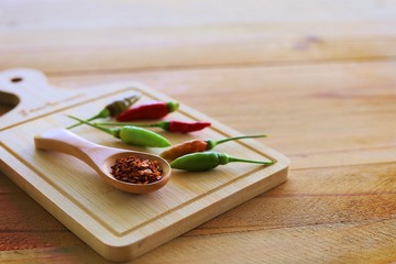 A spoon of cayenne pepper and fresh chilli on wooden background for food ingredients and cooking concept