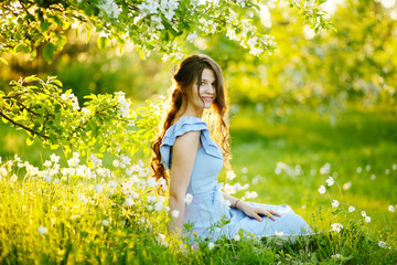 Naklejka na ściany i meble Girl at sunset in a flowering garden