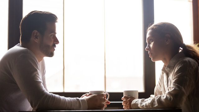 Millennial couple talking in cafe drinking coffee