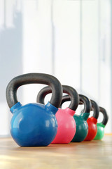 Naklejka na ściany i meble Colorful kettlebells in a row in a gym