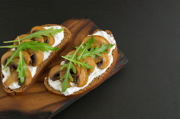 sandwich with soft cheese and mushrooms on a black background.