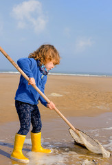cute little girl and her net for shrimp fishing on the beach