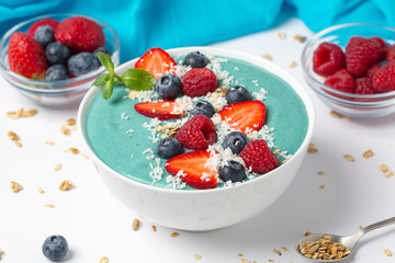 Blue Spirulina and fresh berries smoothie bowl with blueberries, raspberries, strawberries, granola and mint.