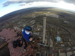 Man without any safety equipment walking on a thin rusted rail on top of a high abandoned stack...