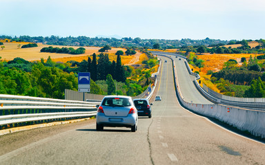 Car on the road at in Sardinia Island in Italy summer. Transport driving on the highway of Europe. View on motorway. Olbia province. Mixed media.