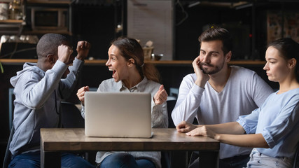 Multiracial friends support different teams watching game in bar