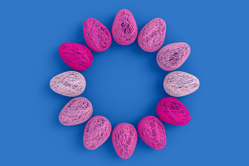 Easter concept. On an blue background a lot of eggs woven from intertwined all shades of pink and white threads laid out in a circle with an empty space in the center. 3D stock illustration.