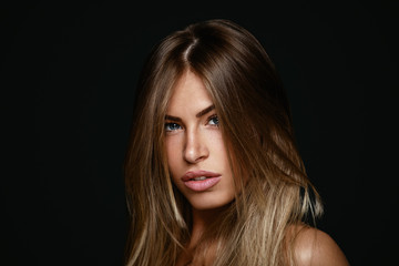 Fototapeta premium Beauty portrait of young blonde in a studio on a dark background