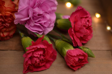Pink, Orange and Red Carnation Flowers Laying on Wood Tray, Close-Up