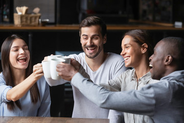 Happy diverse friends say cheers having fun in cafe together