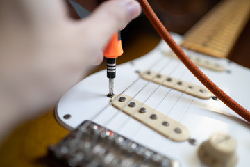 Guitar technician setting the height of guitar pickup