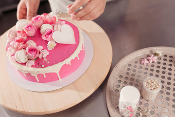 professional woman chef decorating delicious cake with cream and glaze. kitchen portrait