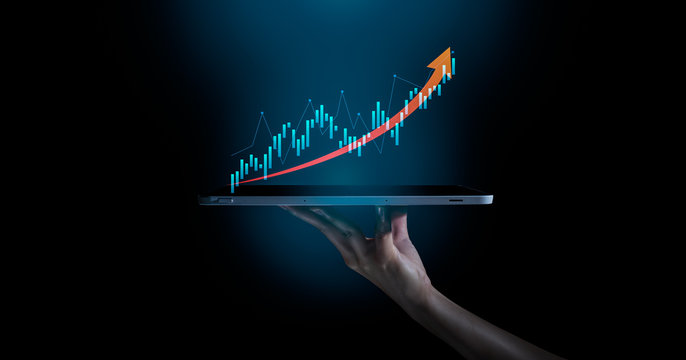 Business evolution to success and growing growth concept.hand holding an empty digital tablet with growth stock graph and rising arrow,Corporate representing business growth.