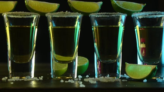 glasses with tequila and salt are on a bar on black background