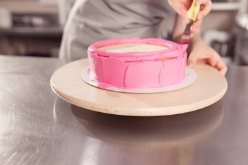 professional woman chef decorating delicious cake with cream and glaze. kitchen portrait