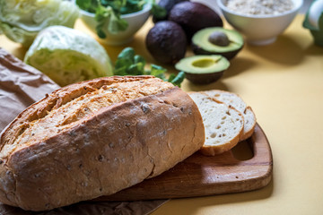 vegetarian breakfast, fresh gluten-free bread, avocado, salad and oatmeal on a yellow background, close-up, horizontal frame, copy space