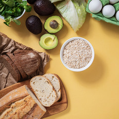 vegetarian breakfast, fresh gluten-free bread, avocado, salad and oatmeal on a yellow background, close-up, horizontal frame, copy space