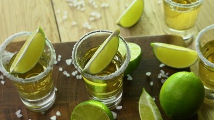 glasses with tequila and salt stand on a wooden table