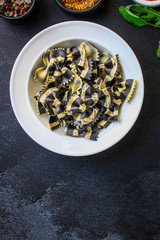 pasta farfalle cuttlefish ink (healthy eating, black multi-colored) menu concept. food background. top view. copy space