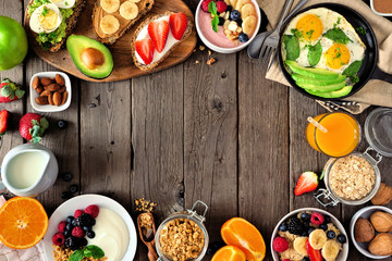 Healthy breakfast food frame. Table scene with fruit, yogurt, smoothie, oatmeal, nutritious toasts and egg skillet. Top view over a rustic wood background. Copy space. - obrazy, fototapety, plakaty
