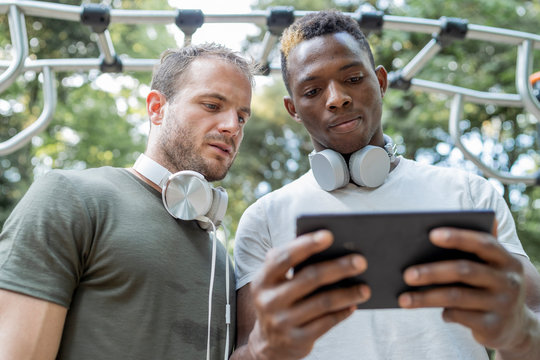 Friends having a break from exercising looking at phablet