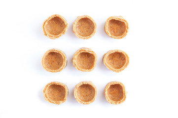 Indian sweets. Small yellow coconut tartlets on a white background.