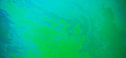 Fototapeta na wymiar Blue, green, yellow color oil patterns on the surface of the water
