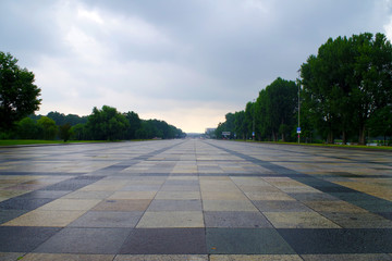 Empty Great Road in Nuremberg (Germany) - known landmark. The granite pavement is colorful and there are many green trees on the sides. It's a cloudy evening.  