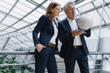 Businessman and businesswoman looking at globe in modern office building