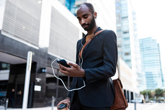 Yung businessman looking at smartphone outdoors