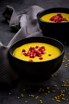 Bowls of vegan lentil soup with ginger, turmeric, coconut milk and pomegranate seeds