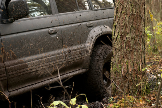 Off-road car going through deep mud holes. Detail of dirty car with filled mud - carwash concept. car wheels. dirty car wheel stands on forest road