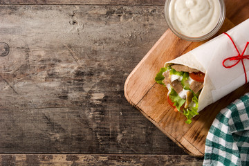 Doner kebab or shawarma sandwich on wooden table. Top view. Copy space	