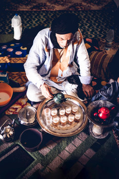 Senior man in Smara refugee camp pouring tea into glasses, Tindouf, Algeria