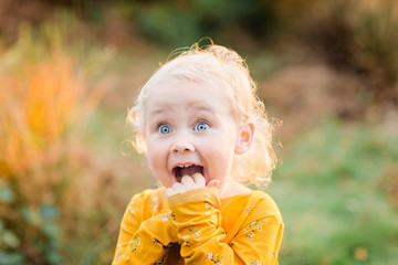Portrait of blond toddler girl with blue eyes pulling funny faces