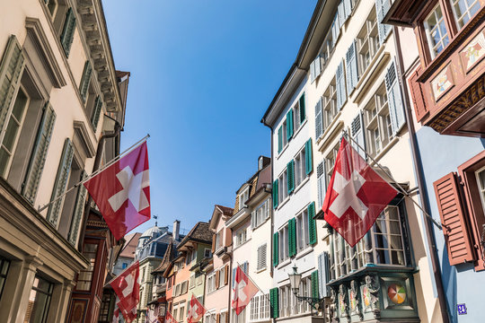 Switzerland, Canton of Zurich, Zurich, Swiss flags hanging over historic Augustinergasse lane