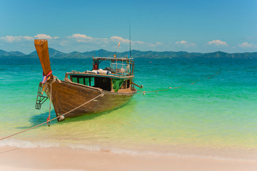 Naklejka na ściany i meble Traditional Thai longtail boat moored on exotic beach.