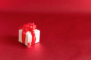 Gift box with bow on red colored background. Holiday present concept.