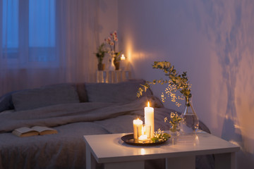 night interior of bedroom with flowers and burning candles