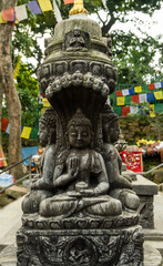 Ancient carved stone pillar with the image of a sitting Buddha and are decorated with traditional Buddhist patterns.