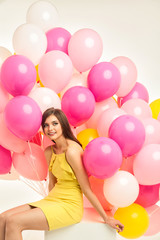 colorful portrait of young beautiful model with a lot of pink yellow and white baloons