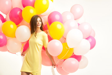 Fototapeta na wymiar colorful portrait of young beautiful model with a lot of pink yellow and white baloons