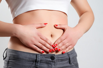 a young woman massages her stomach with two hands. isolated on white background
